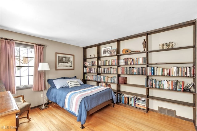 bedroom featuring wood finished floors, visible vents, and baseboards