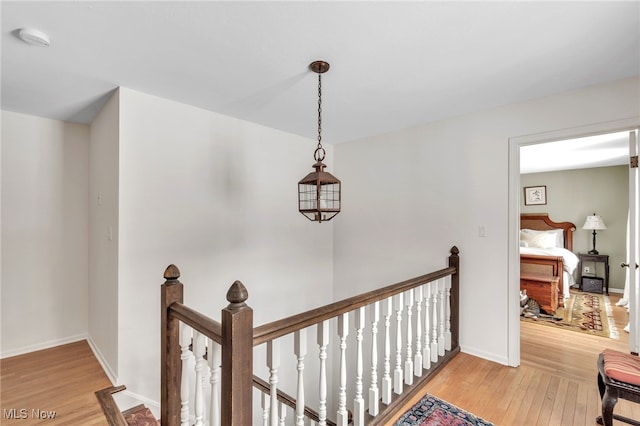 corridor featuring an upstairs landing, light wood-style flooring, and baseboards