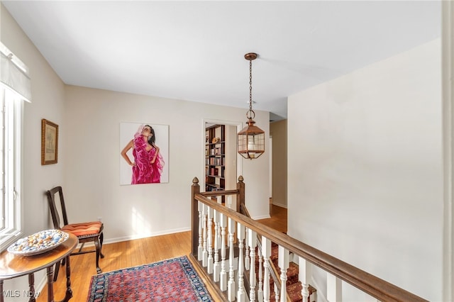 corridor featuring an upstairs landing, baseboards, and light wood-style floors