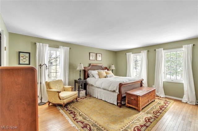 bedroom featuring light wood-type flooring, multiple windows, and baseboards