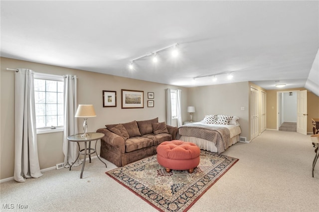 bedroom with light carpet, rail lighting, and baseboards