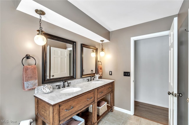 bathroom featuring tile patterned floors, double vanity, baseboards, and a sink