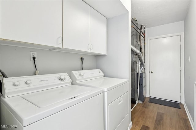 washroom featuring cabinet space, wood finished floors, and washing machine and clothes dryer