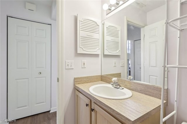 bathroom with a closet, radiator, wood finished floors, and vanity