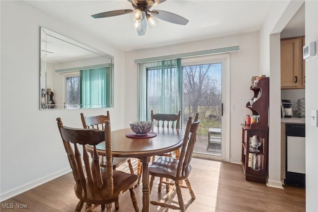 dining room with a healthy amount of sunlight, a ceiling fan, light wood-type flooring, and baseboards