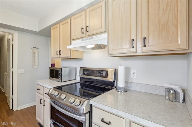 kitchen with light brown cabinets, under cabinet range hood, light countertops, wood finished floors, and stainless steel appliances