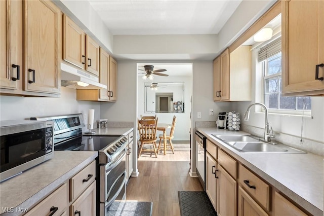 kitchen with under cabinet range hood, stainless steel appliances, light countertops, and a sink