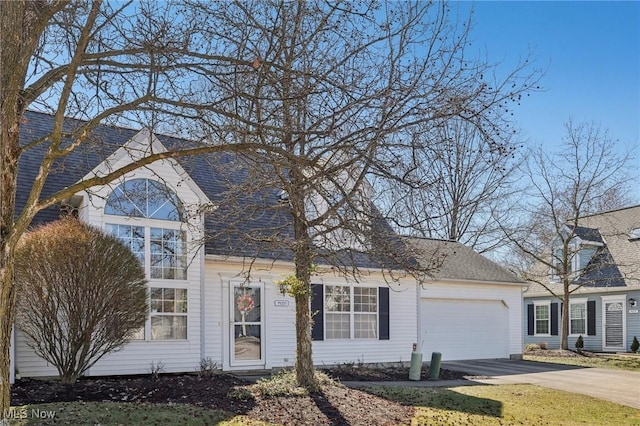 view of front facade with a garage, concrete driveway, and a shingled roof