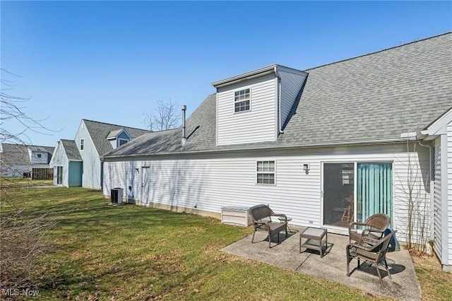 rear view of property featuring central AC unit, a lawn, a shingled roof, and a patio