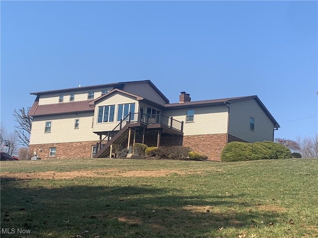 back of house with a deck, stairs, a yard, brick siding, and a chimney