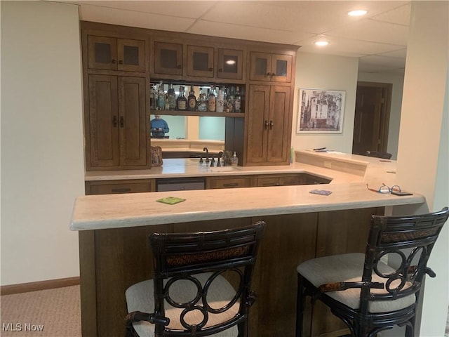 bar featuring a sink, a drop ceiling, wet bar, baseboards, and dishwasher