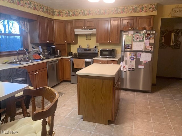 kitchen with light tile patterned floors, a sink, stainless steel appliances, light countertops, and under cabinet range hood