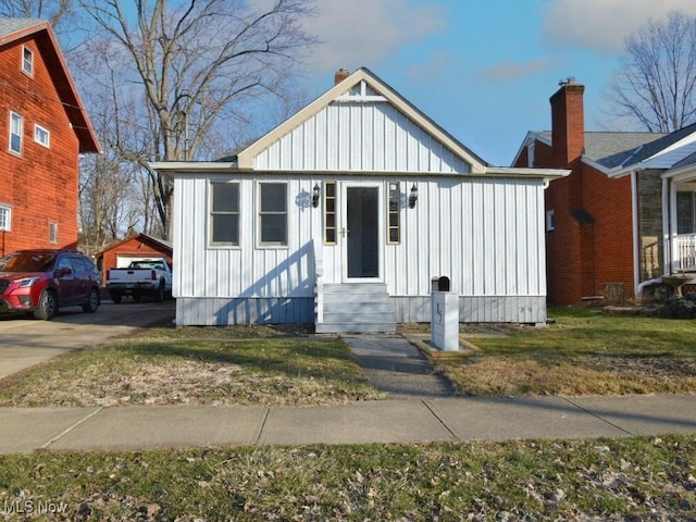 bungalow-style home with a front lawn, board and batten siding, driveway, and entry steps