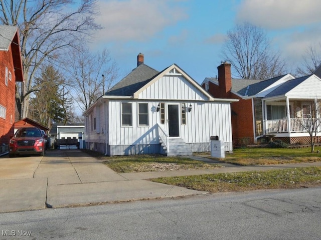 bungalow-style home with entry steps, board and batten siding, an outdoor structure, and roof with shingles