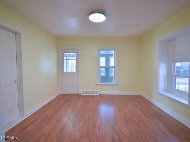 spare room with visible vents, a healthy amount of sunlight, baseboards, and wood finished floors