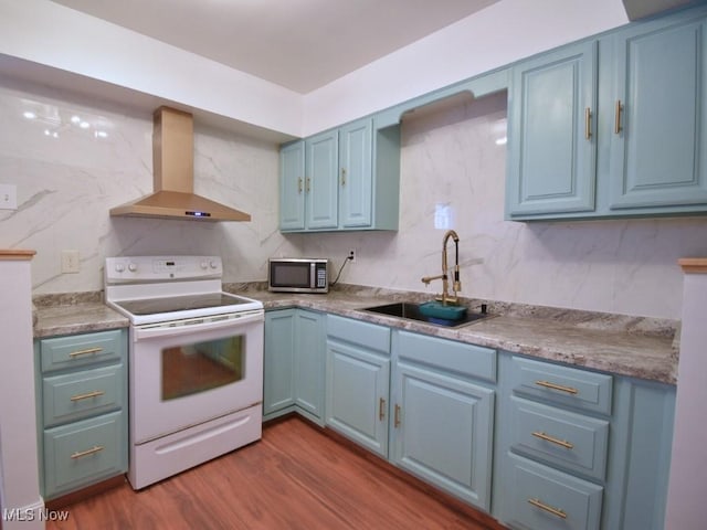 kitchen featuring blue cabinetry, a sink, electric stove, stainless steel microwave, and wall chimney exhaust hood