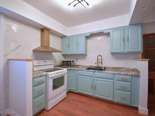 kitchen featuring blue cabinetry, a sink, electric stove, stainless steel microwave, and exhaust hood