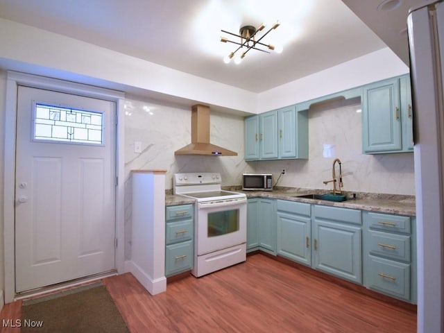 kitchen with white electric range oven, blue cabinetry, a sink, stainless steel microwave, and wall chimney exhaust hood