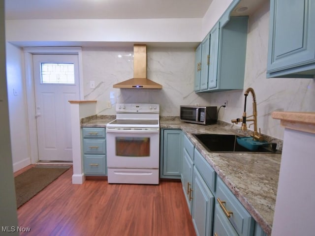 kitchen with blue cabinetry, stainless steel microwave, wall chimney exhaust hood, and electric stove