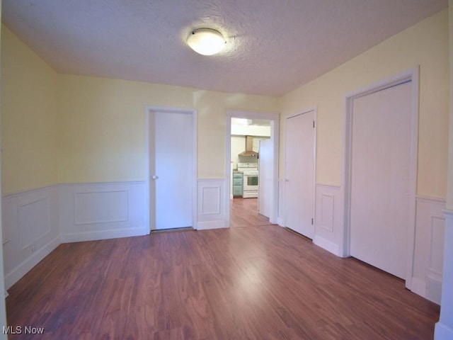 unfurnished room featuring a wainscoted wall, a textured ceiling, and wood finished floors