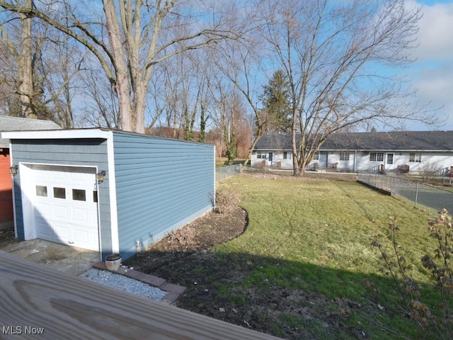 view of yard with a detached garage, an outbuilding, and fence