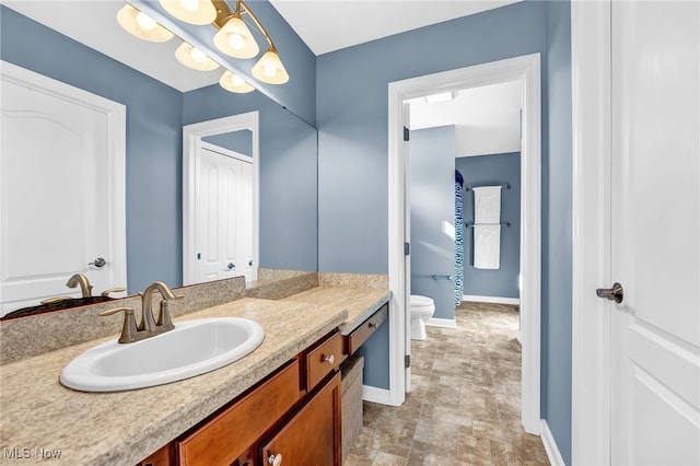 bathroom featuring baseboards, toilet, and vanity