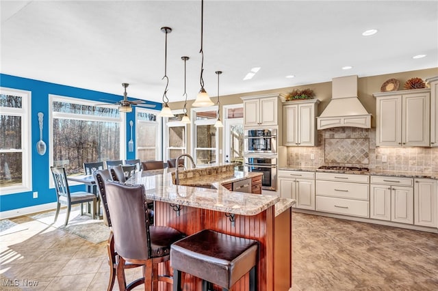 kitchen with premium range hood, stainless steel appliances, a sink, a kitchen breakfast bar, and tasteful backsplash