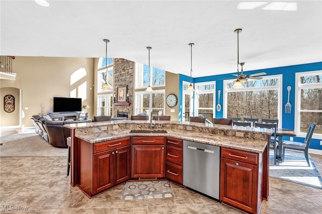 kitchen featuring a sink, stainless steel dishwasher, open floor plan, reddish brown cabinets, and a fireplace