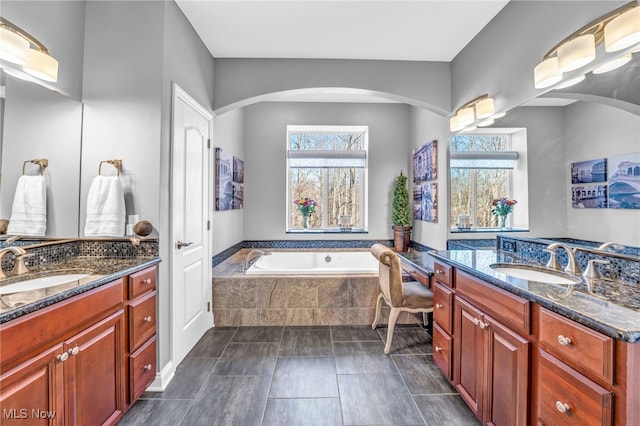 full bath featuring a sink, two vanities, and a bath