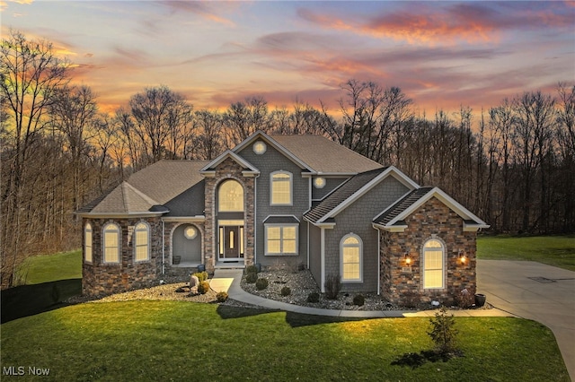 view of front of property featuring a lawn, driveway, and roof with shingles