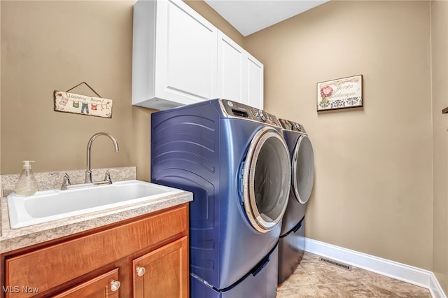 clothes washing area featuring visible vents, a sink, cabinet space, separate washer and dryer, and baseboards