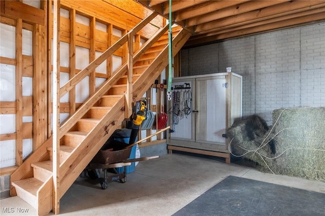 basement featuring stairs and brick wall