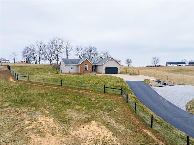 view of yard with a rural view, fence, a garage, and driveway