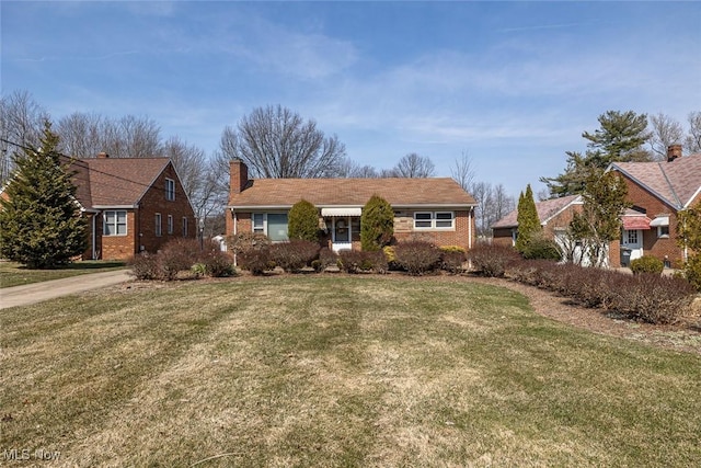 view of front of property featuring a front lawn, brick siding, and a chimney