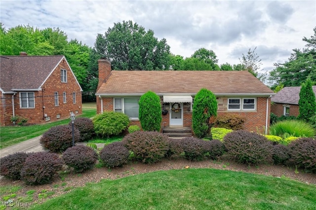 view of front facade with a front yard, brick siding, and a chimney