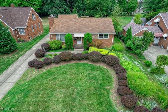 view of front of home featuring a front yard, brick siding, driveway, and a chimney