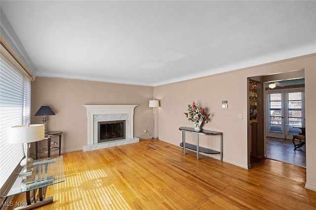 living room featuring wood finished floors, baseboards, and a high end fireplace