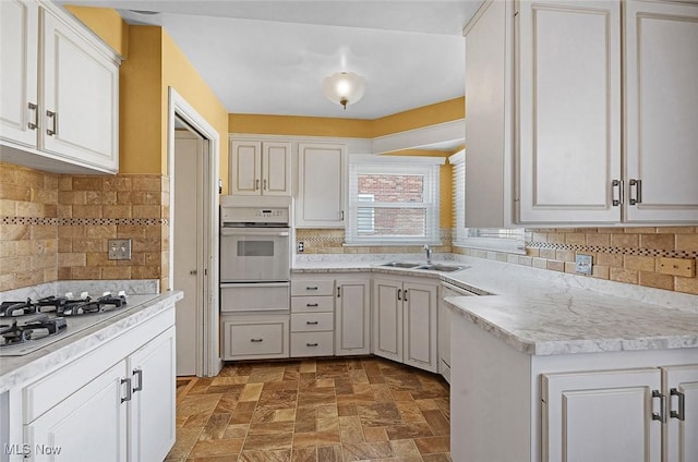 kitchen with white appliances, a warming drawer, light countertops, and a sink