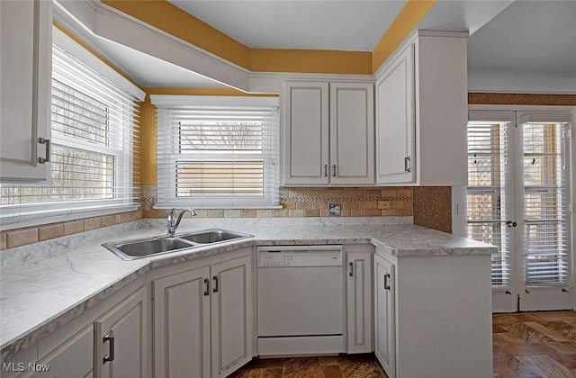 kitchen featuring a wealth of natural light, a sink, white cabinets, and white dishwasher