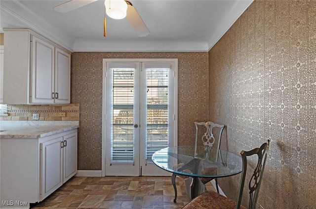 unfurnished dining area with stone finish flooring, ceiling fan, and french doors