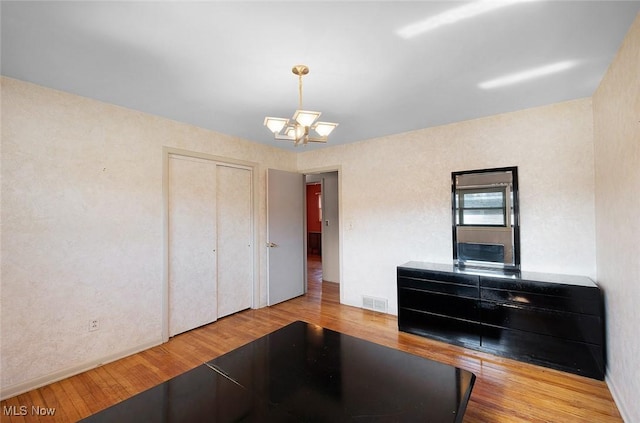 interior space with wood finished floors, visible vents, a closet, and a chandelier