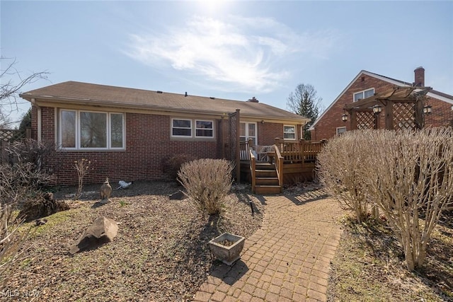 rear view of property featuring a deck and brick siding