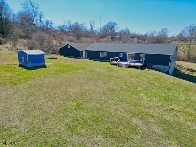 exterior space featuring a deck, an outbuilding, and a yard