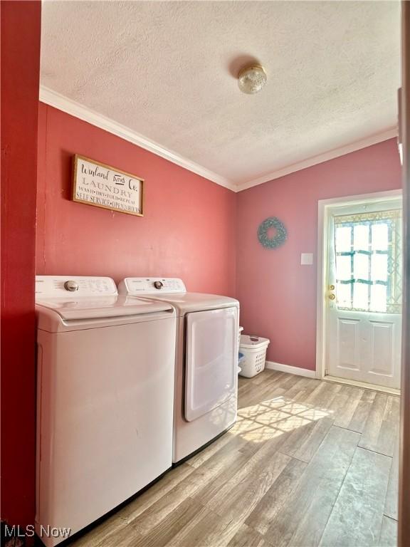 laundry room featuring washing machine and clothes dryer, laundry area, light wood-style flooring, a textured ceiling, and crown molding