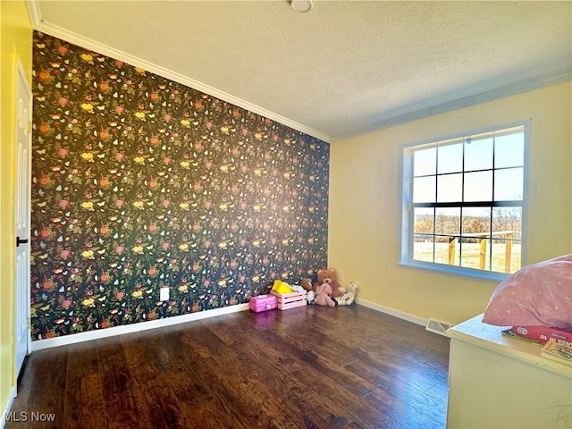 interior space featuring a textured ceiling, crown molding, baseboards, and wood finished floors