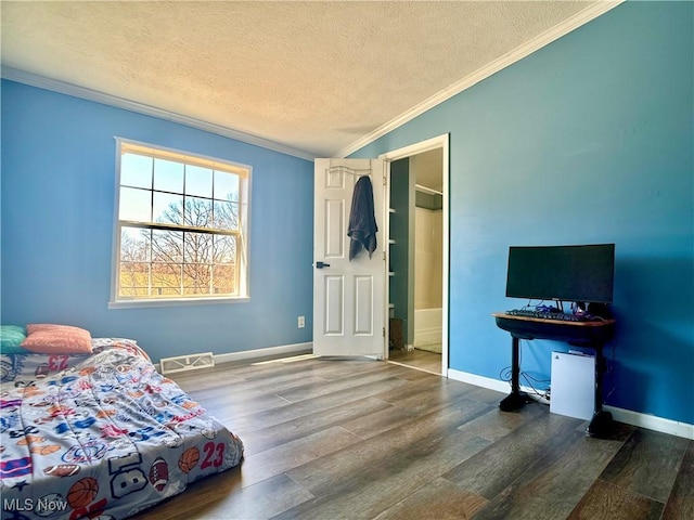 bedroom featuring wood finished floors, visible vents, ornamental molding, vaulted ceiling, and a textured ceiling