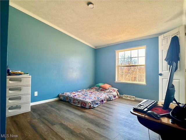 bedroom featuring a textured ceiling, baseboards, dark wood-style flooring, and ornamental molding