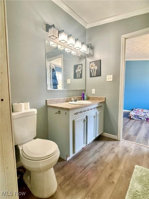 bathroom featuring vanity, toilet, wood finished floors, and crown molding