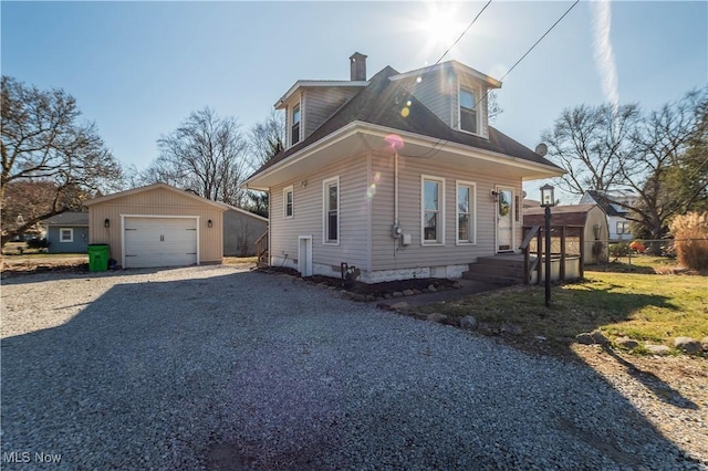 view of front of home with gravel driveway, an outbuilding, a detached garage, and a chimney