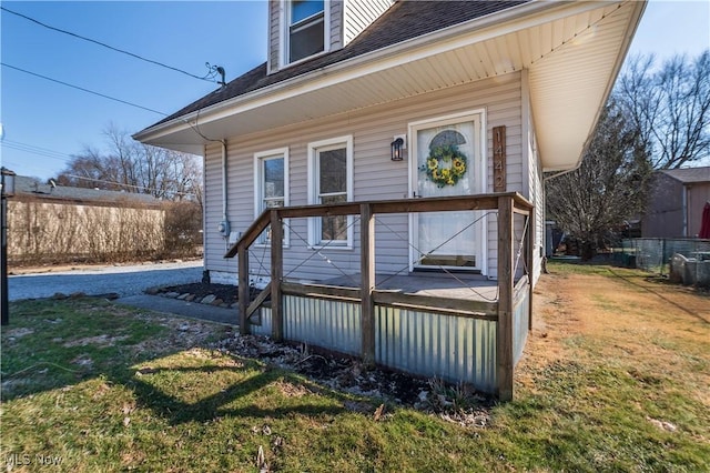 doorway to property featuring a shingled roof and a yard